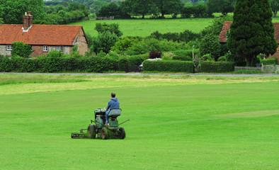 Man Mowing grass on an English Cricket field