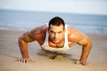 Fototapeta na wymiar Man doing push ups on a beach