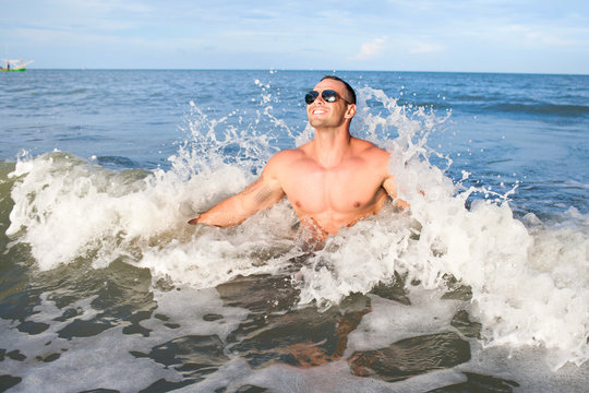 Happy muscular male enjoying the sea