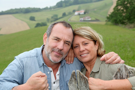 Senior couple leaning on fence in countryside