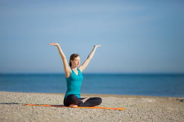 Fototapeta na wymiar Young woman doing yoga on beach