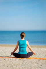 Fototapeta na wymiar Young woman meditating on the beach .