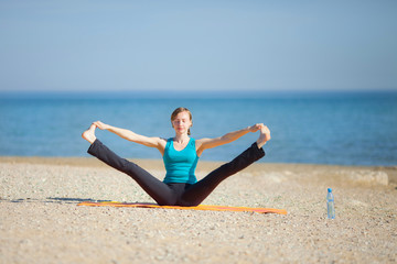 Fototapeta na wymiar Young woman doing yoga on beach