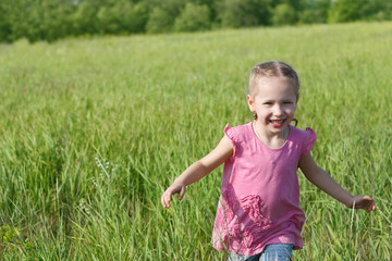 Happy little child running in the field over green grass