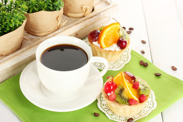 cup of coffee and sweet cakes with fruits on wooden table