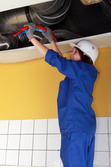 Plumber running pipes across a ceiling