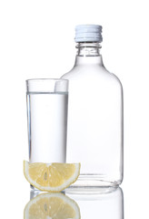Bottle of vodka and wineglass with lemon isolated on white