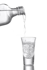 Vodka poured into a glass isolated on white
