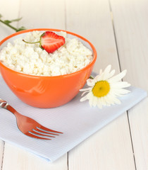 cottage cheese with strawberry in orange bowl, fork and flower