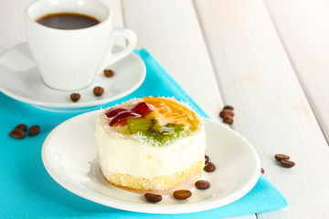 cup of coffee and sweet cakes with fruits on wooden table