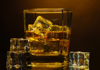 glass of scotch whiskey and ice on brown background