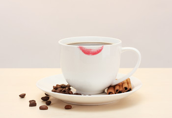 cup of coffee with lipstick mark beans and cinnamon sticks