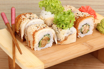 Tasty rolls served on wooden plate on wooden background
