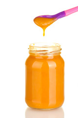 Jar with baby food and spoon on white background close-up