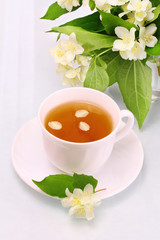 White cup with jasmine tea and flowers