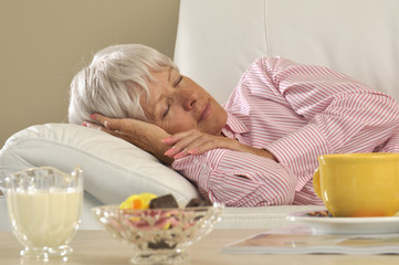 Obraz na płótnie Canvas Seniorin entspannt sich auf einem Sofa