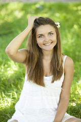 Naklejka na ściany i meble Beautiful teen girl in the park at green grass.