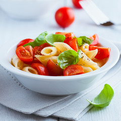 Pasta salad with cherry tomatoes and basil leaves