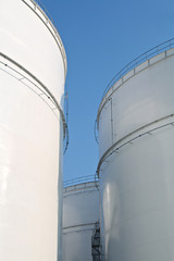 Tall white storage tanks at an oil refinery