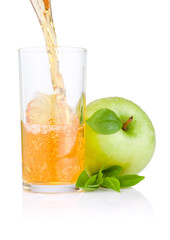 Pouring apple juice into a glass, green apples with green leaf o