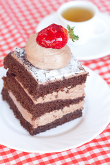beautiful cake with strawberry and tea on plaid fabric