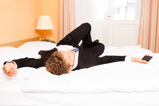 Geschäftsmann liegt erschöpft auf Hotel-Bett