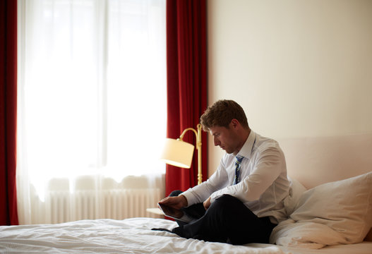 junger Mann mit Tablet-PC auf Hotelzimmer