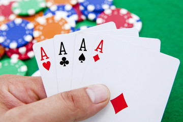 poker, four aces holded in hand over a casino table full with ch