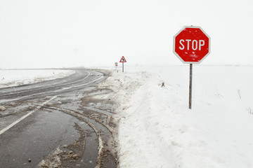 Crossroad in a stormy winter day with stop sign