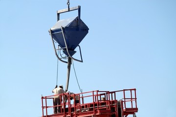 Maçons manoeuvrant une trémie de charge à béton