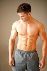 Obraz premium Portrait of muscular sporty man standing on brown