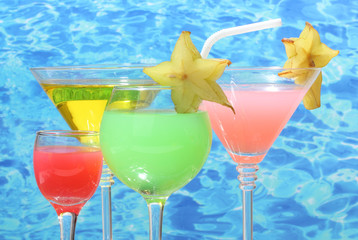 Glasses of cocktails on table on blue sea background