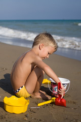 A little boy on a beach builds locks