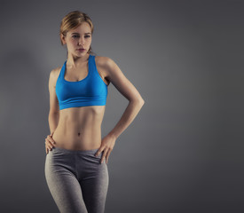 junge frau in fitness dress vor grauem hintergrund