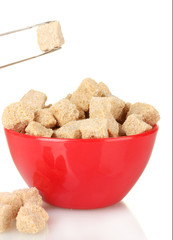 brown cane sugar cubes in bowl with sugar-tongs