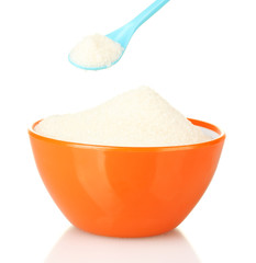 A colorful bowl full of white sugar with bright spoon