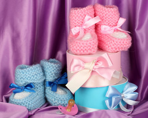 pink and blue baby boots, pacifier and gifts on silk