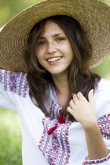 Slav teen girl at green meadow in national ukrainian clothing.