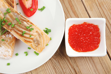 salmon steaks on white dish with red caviar