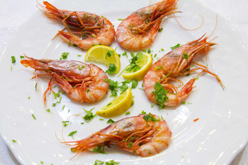 Shrimps with lemon slices and parsley on white plate