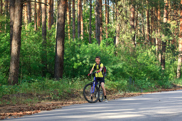 A teenager on a bicycle traveling in the forest