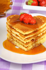 Stack of heart shaped pancakes with syrup and strawberry