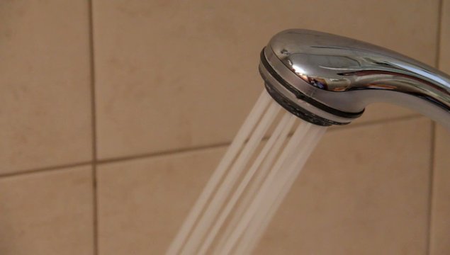 Closeup of a shower head with sprinkling water.