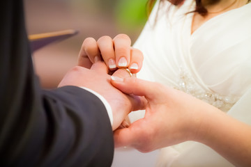 Groom puts ring on brides finger in church