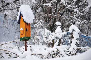orange birdhouse covered with snow