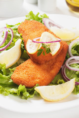 Breaded fish steaks with lemon and lettuce