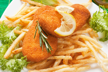 Breaded fish steaks with french fries, lemon and lettuce