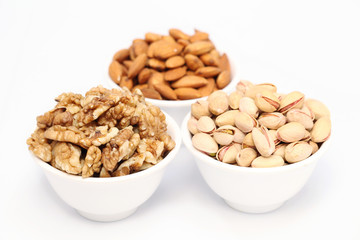 Bowls of almonds,walnuts and pistachios on white background