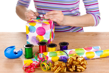 Wrapping presents surrounded by  paper, ribbon and bows