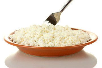 Fork scoops of cottage cheese in a plate on white background